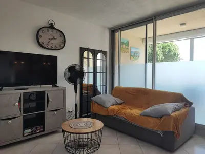 a living room with a couch and a tv and a clock at Studio spacieux à Gruissan - Parking - Vue port - Proche plage - FR-1-796-29 in Gruissan