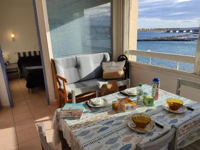 a dining room with a table and a view of the water at Gruissan: T2 Spacieux 4/5 Pers, Proche Plage Grazel, Parking Privé - FR-1-796-34 in Gruissan