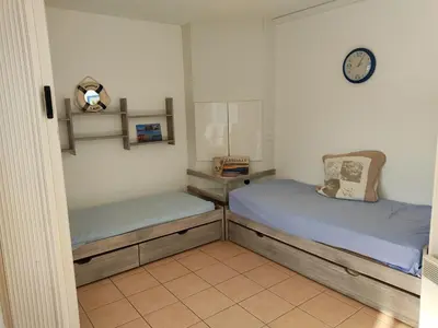 a bedroom with two beds and a clock on the wall at Gruissan: T2 Spacieux 4/5 Pers, Proche Plage Grazel, Parking Privé - FR-1-796-34 in Gruissan