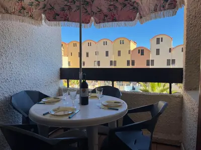 a table with a bottle of wine sitting on it at Studio Familial Piscine, Parking, Proche Plage - Idéal 4 pers, Budget Serré, Gruissan - FR-1-796-58 in Gruissan