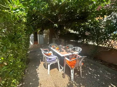 a table and chairs sitting under a tree at **Gruissan - T2 Cabine Mezzanine - Côté Village - 6 pers - Parking Privé - Proche Plages** - FR-1-796-63 in Gruissan
