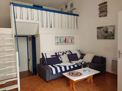 a living room with a couch and a loft bed at **Gruissan - T2 Cabine Mezzanine - Côté Village - 6 pers - Parking Privé - Proche Plages** - FR-1-796-63 in Gruissan