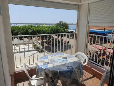 a table and chairs on a balcony with a view of the beach at Gruissan - Appartement climatisé - 6 pers - Parking - Plage à 50m - FR-1-796-51 in Gruissan