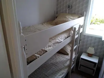 a bunk bed in a small room with a window at Gruissan - Appartement climatisé - 6 pers - Parking - Plage à 50m - FR-1-796-51 in Gruissan