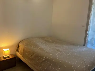a bedroom with a bed and a lamp on a night stand at Appartement T2 moderne avec piscines, garage et proche plage - Gruissan - FR-1-796-43 in Gruissan