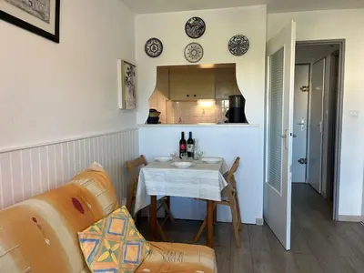 a living room with a table and a kitchen at Appartement T2 moderne avec piscines, garage et proche plage - Gruissan - FR-1-796-43 in Gruissan