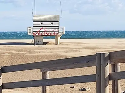 a chair sitting on the beach next to a fence at Appartement T2 moderne avec piscines, garage et proche plage - Gruissan - FR-1-796-43 in Gruissan
