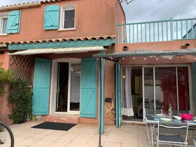 a house with blue doors and a table on a patio at Villa Confortable 6 Pers. Climatisée, Proche Plage du Grazel, Calme, Tout Équipée, Stationnement Inclus - FR-1-796-71 in Gruissan