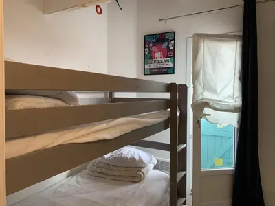 a bunk bed room with two bunk beds and a window at Villa Confortable 6 Pers. Climatisée, Proche Plage du Grazel, Calme, Tout Équipée, Stationnement Inclus - FR-1-796-71 in Gruissan