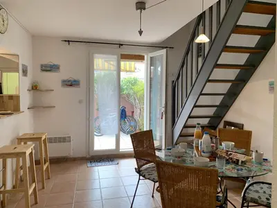 a kitchen and dining room with a table and a staircase at Villa Confortable 6 Pers. Climatisée, Proche Plage du Grazel, Calme, Tout Équipée, Stationnement Inclus - FR-1-796-71 in Gruissan