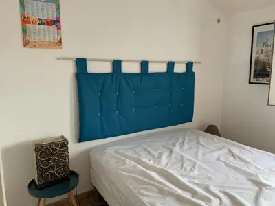 a bedroom with a bed with a blue headboard at Villa Confortable 6 Pers. Climatisée, Proche Plage du Grazel, Calme, Tout Équipée, Stationnement Inclus - FR-1-796-71 in Gruissan