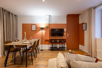 a dining room with a table and chairs and a tv at L'Occitane - Grand Studio Chaleureux en Hyper centre in Castres