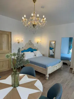 a bedroom with a bed and a table and a chandelier at Appartement du Cloitre 1er in Narbonne