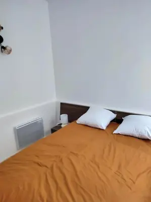 a bedroom with an orange bed with two pillows at Charmant T2 au cœur de Narbonne in Narbonne