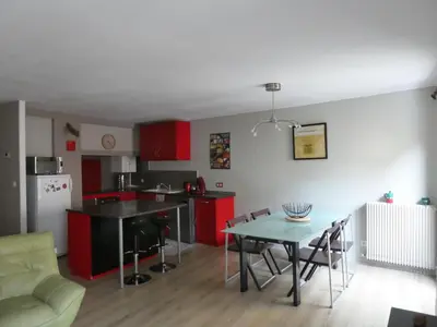 a kitchen and dining room with red cabinets and a table at La Courtine, centre historique Narbonne in Narbonne