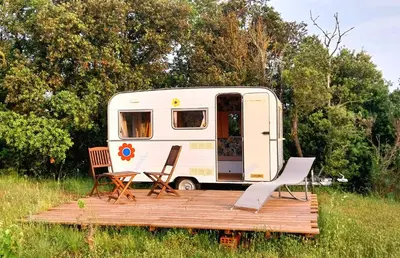 an rv with two chairs and a wooden deck at La Caravane d'Alon in Magrie