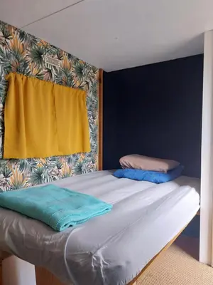 a bed in a room with a yellow curtain at La Caravane d'Alon in Magrie
