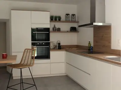 a kitchen with white cabinets and a chair in it at Le Moulin, avec parc, piscine, au cœur du village in Villegly