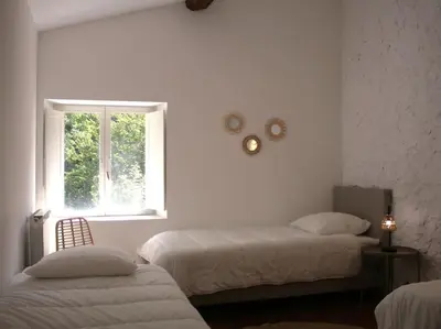 a white room with two beds and a window at Le Moulin, avec parc, piscine, au cœur du village in Villegly