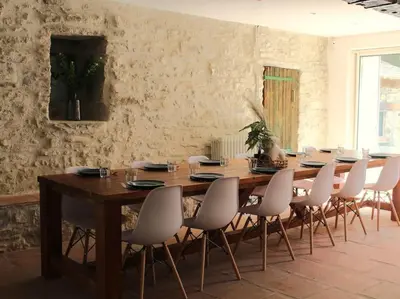 a dining room with a wooden table and white chairs at Le Moulin, avec parc, piscine, au cœur du village in Villegly