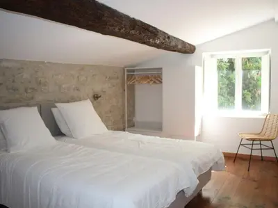 a bedroom with a white bed and a chair at Le Moulin, avec parc, piscine, au cœur du village in Villegly