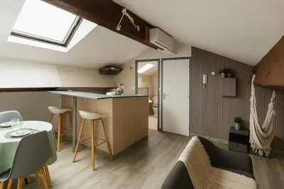 a kitchen and living room with a table and chairs at Sous les toits in Narbonne