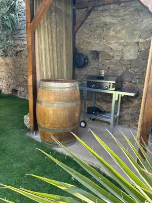 a wooden barrel sitting next to a table and a grill at La Vade in Carcassonne