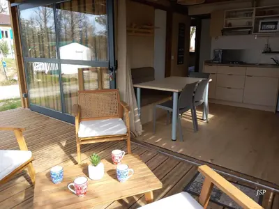 a porch with a table and chairs and a kitchen at Chalet Zen in Vaudreuille