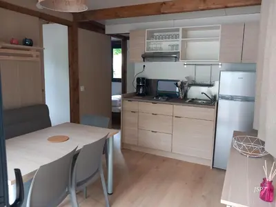 a small kitchen with a table and a refrigerator at Chalet Zen in Vaudreuille