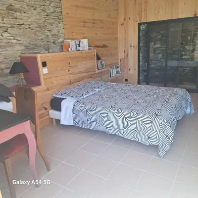 a bedroom with a bed and a wooden wall at Au Grand Mûrier in Roquefère