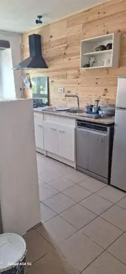 a kitchen with white appliances and wooden walls at Au Grand Mûrier in Roquefère