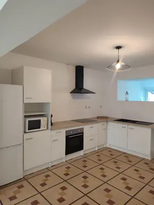 an empty kitchen with white cabinets and a refrigerator at Au coeur de l'occitanie in Cuq