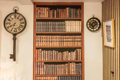 a book shelf filled with books next to a clock at Escape Game & Room - Cathédrale - Grands Buffets - Narbonne in Narbonne