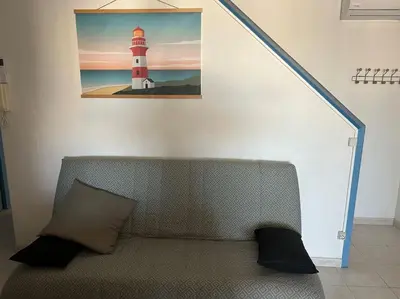 a couch in a room with a picture of a lighthouse at L'Albatros in Gruissan