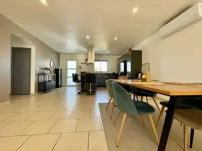 a dining room and living room with a table and chairs at Villa des Perdrix - Piscine et Clim - 120m2 in Lavalette