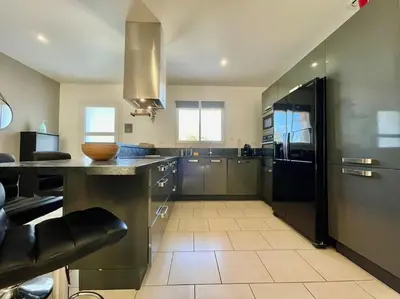 a large kitchen with stainless steel appliances and a counter at Villa des Perdrix - Piscine et Clim - 120m2 in Lavalette
