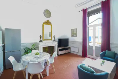 a living room with a table and chairs and a tv at Appartement du Forum,La gare, 50 m2 , Climatisation, Garage, Cour in Narbonne