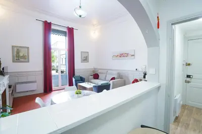 a living room with white walls and a large window at Appartement du Forum,La gare, 50 m2 , Climatisation, Garage, Cour in Narbonne