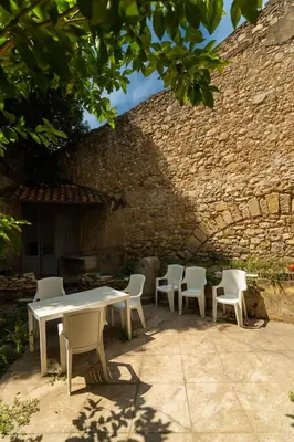 a table and chairs sitting next to a brick wall at Appartement du Forum,La gare, 50 m2 , Climatisation, Garage, Cour in Narbonne