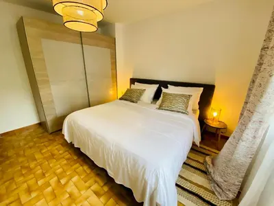 a bedroom with a large white bed and a chandelier at Maison Rosy in Carcassonne