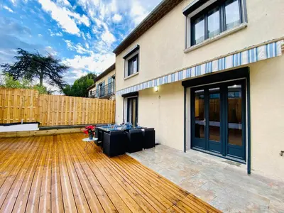 a patio with a table on a wooden deck at Maison Rosy in Carcassonne