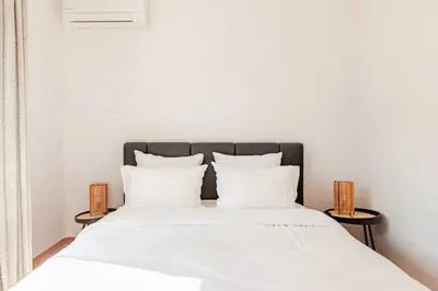 a bedroom with a bed with white sheets and pillows at Maison Rosy in Carcassonne