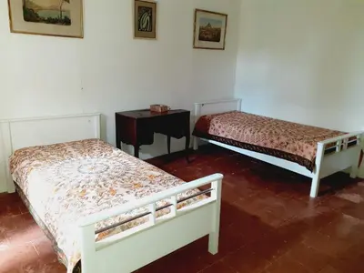 two beds in a room with a night stand and a table at Location maison de campagne 5 personnes in Quarante