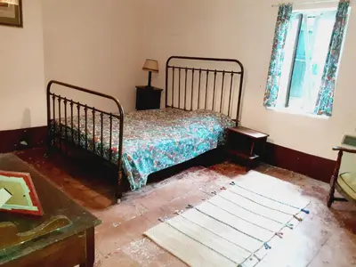 a bedroom with a bed and a window and a rug at Location maison de campagne 5 personnes in Quarante
