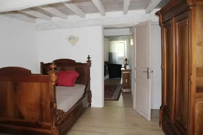 a bedroom with a wooden bed and an open door at La Maison de Berthe - Havre de paix dans la campagne - Entièrement rénovée et équipéé in Montmaur