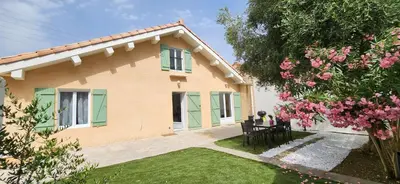 a woman sitting at a table in front of a house at Villa Papillons Narbonne Centre in Narbonne