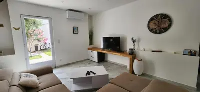 a living room with a couch and a clock on the wall at Villa Papillons Narbonne Centre in Narbonne