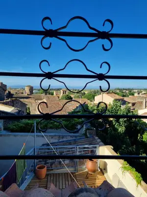 a view through a iron gate of a balcony with stairs at Maison de charme in Caunes-Minervois