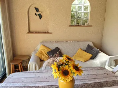a living room with a table with a vase of flowers at Charmante villa T2 mezzanine avec cour, jardin, véranda, barbecue et parking privé, proche plage et commerces - FR-1-797-2 in Port-la-Nouvelle