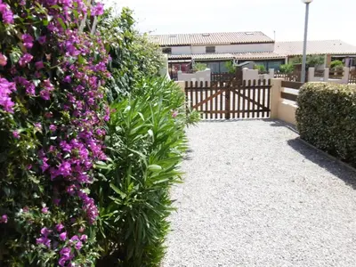 a garden with purple flowers and a fence at Charmante villa T2 mezzanine avec cour, jardin, véranda, barbecue et parking privé, proche plage et commerces - FR-1-797-2 in Port-la-Nouvelle
